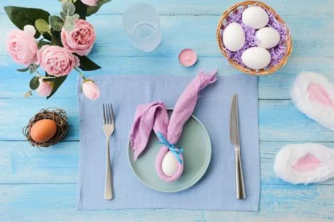 Easter table setting, egg with bunny ears on plate on table decorated for E.. Stock Photos