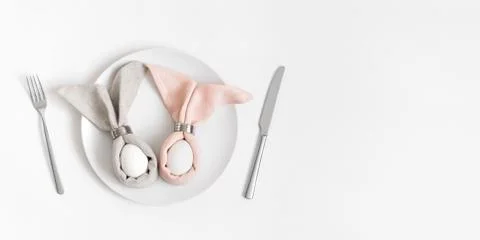 Easter table setting with egg in Easter bunny napkin on a white background. Stock Photos