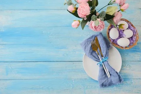 Easter table setting, eggs with cutlery on plate on table decorated for Easte Stock Photos