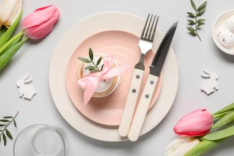 Easter table setting with eggs, tulip flowers and olive branches on grey back Stock Photos