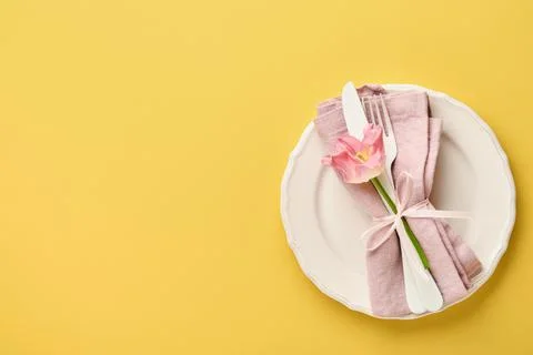 Easter table setting with floral decor on yellow table. Elegance dinner. Mock Stock Photos