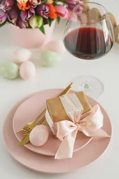 Easter Table Setting with Gift Box, Decorated Eggs, Wine Glass and Tulips. .. Stock Photos