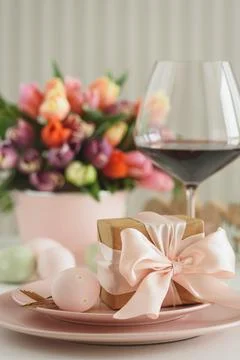 Easter Table Setting with Gift Box, Decorated Eggs, Wine Glass and Tulips. .. Stock Photos
