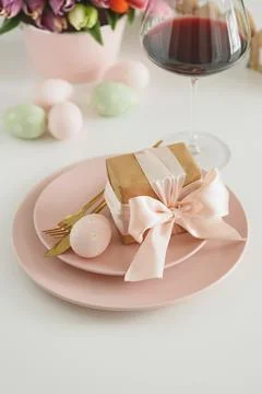 Easter Table Setting with Gift Box, Decorated Eggs, Wine Glass and Tulips. .. Stock Photos