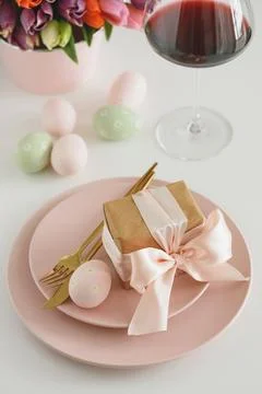 Easter Table Setting with Gift Box, Decorated Eggs, Wine Glass and Tulips. .. Stock Photos