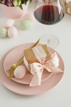 Easter Table Setting with Gift Box, Decorated Eggs, Wine Glass and Tulips. .. Stock Photos