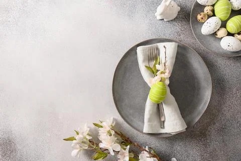 Easter table setting with gray plate, spring flowers and green colorful eggs. Stock Photos