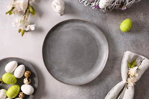 Easter table setting with gray plate, spring flowers and green colorful eggs. Stock Photos