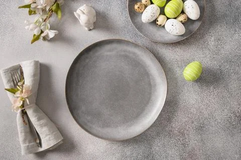 Easter table setting with gray plate, spring flowers and green colorful eggs. Stock Photos