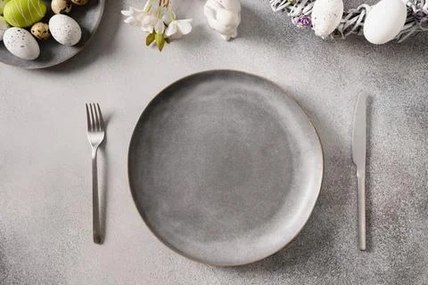 Easter table setting with gray plate, spring flowers and green colorful eggs. Stock Photos