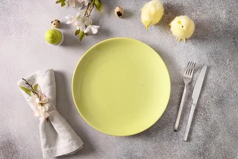 Easter table setting with gray plate, spring flowers and green colorful eggs. Stock Photos
