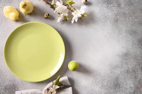 Easter table setting with gray plate, spring flowers and green colorful eggs. Stock Photos