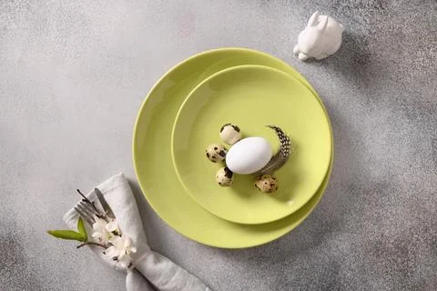 Easter table setting with gray plate, spring flowers and green colorful eggs. Stock Photos