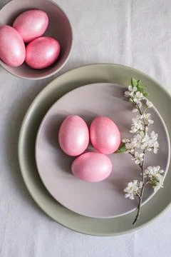 Easter table setting with minimalist floral decor. Pastel pink Easter eggs in Stock Photos