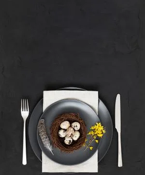 Easter table setting with a nest of quail eggs , a feather, a napkin  Stock Photos