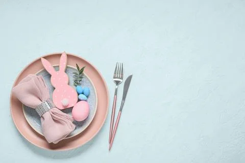 Easter table setting with painted eggs, olive branch and wooden rabbit on lig Stock Photos