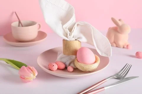 Easter table setting with painted eggs, tulip flower and toy rabbit on color  Stock Photos