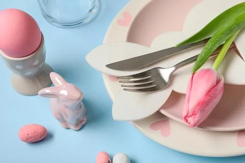 Easter table setting with paper bunny, eggs and tulip flower on blue backgrou Stock Photos