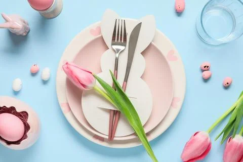 Easter table setting with paper bunny, eggs and tulip flowers on blue backgro Stock Photos