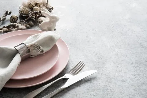Easter table setting with pink plate and golden eggs on grey stone table. Stock Photos