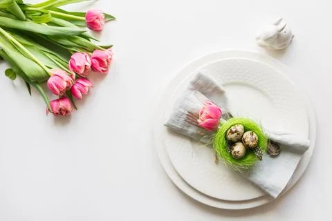 Easter table setting with pink tulip on white. Spring romantic dinner. Stock Photos