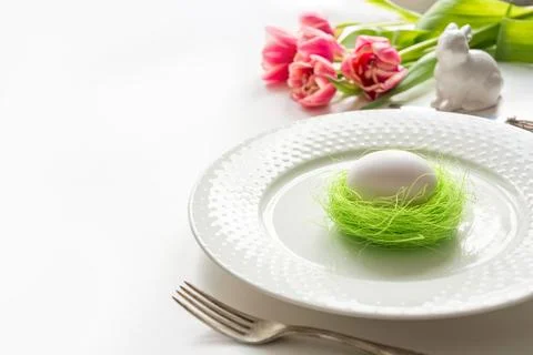 Easter table setting with pink tulip on white. Spring romantic dinner. Stock Photos