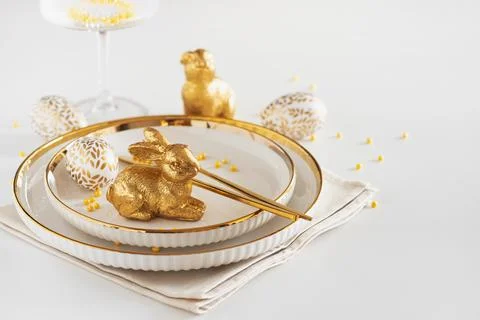 Easter Table Setting with Plates and Golden Decor on White Table Fotos Stock