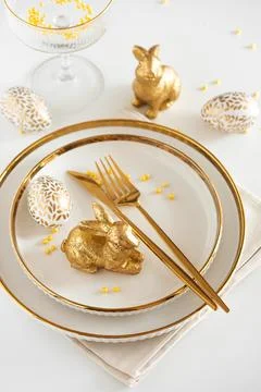 Easter Table Setting with Plates and Golden Decor on White Table Stock-Fotos