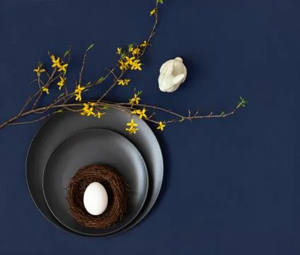 Easter table setting with a white egg in a nest , a porcelain rabbit  Stock Photos