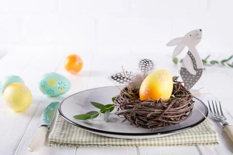 Easter table setting with  white plate, textile napkin yellow decorative eggs Stock Photos