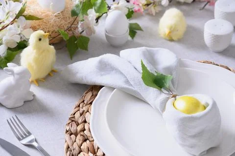 Easter table setting with yellow chick,decorations, fresh flowers and eggs. Stock Photos