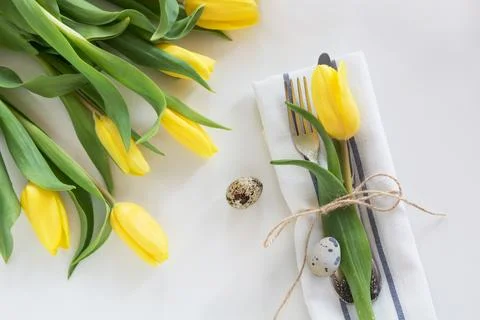 Easter table setting with yellow tulip on white background. Spring dinner. Stock Photos