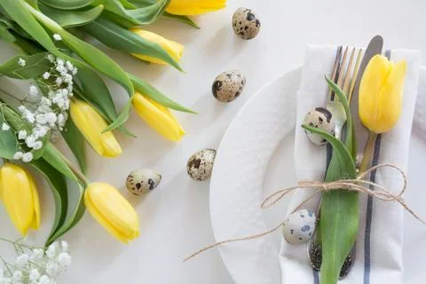 Easter table setting with yellow tulip on white background. Spring dinner. Stock Photos