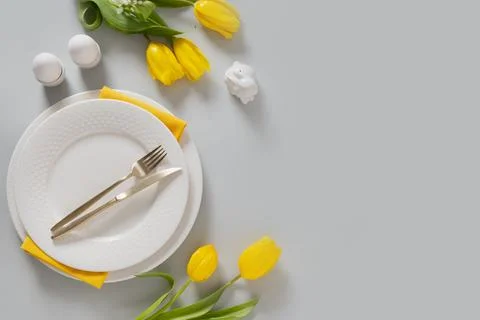 Easter table setting with yellow tulips, white plate, eggs and bunny. Stock Photos