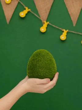 Easter theme. Big egg, grass texture, in human hands on green background. Fotos de archivo