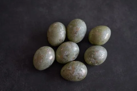 Easter theme. Metallic decorative eggs on dark surface. Stock Photos