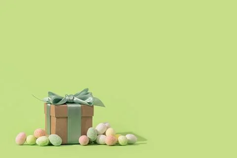 Easter tiny eggs sweets and gift box on green background. Stock Photos
