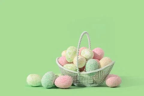 Easter tiny eggs sweets in a basket on green background. Stock Photos