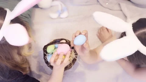 Easter traditions. Two teens with bunny ears playing with Easter colorful eggs Stock Footage 236341720
