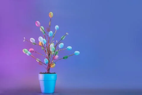 Easter tree decor in blue pot with colorful eggs in neon colors light. Purple Stock Photos