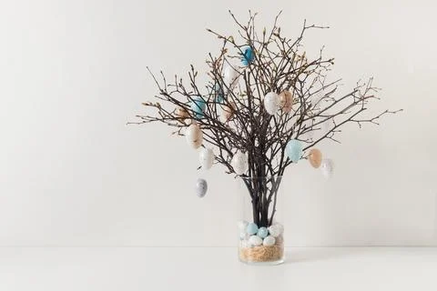 Easter tree decorated white and beige eggs in vase on white table. Stock Photos