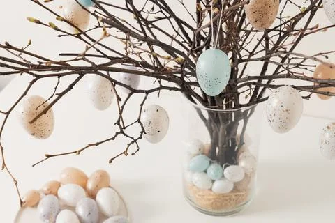 Easter tree decorated white and beige eggs in vase on white table. Close up. Stock Photos