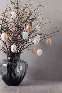 Easter tree decorated white and beige eggs in dark vase on gray background. Stock Photos