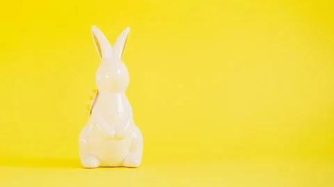Easter white ceramic rabbit on a yellow background. Festive spring background Stock Photos