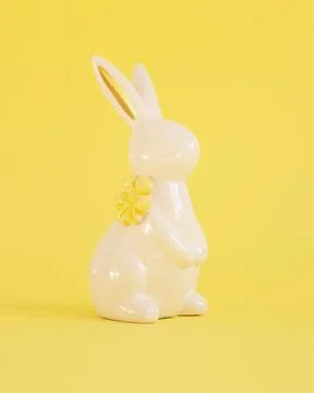 Easter white ceramic rabbit on a yellow background. Festive spring background Stock Photos