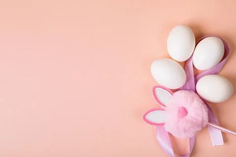 Easter. White eggs with an artificial rabbit on a uniform background. Stock Photos
