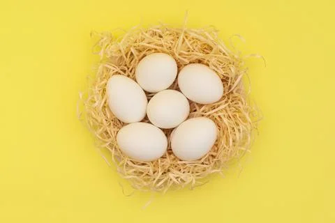 Easter white eggs in straw nest on yellow background. Easter background in Stock Photos