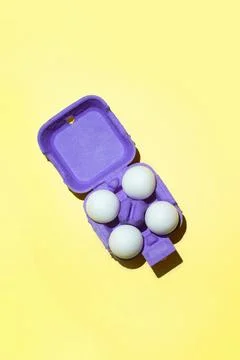 Easter white eggs in violet package on yellow background. Top view. 写真素材