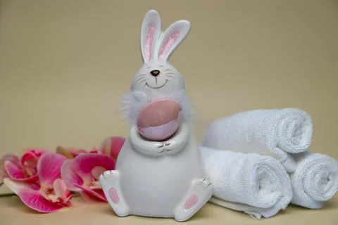 Easter white hare with brown egg on background of orchid flowers white towels Stock Photos