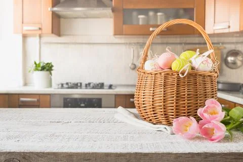 Easter wicker basket with eggs and tulips on kitchen wooden tabletop. Spring. Stock Photos